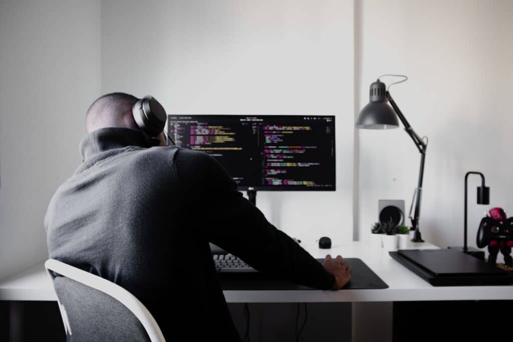 Ein Mann sitzt vor seinem Computerbildschirm auf dem Programmcode gezeigt wird